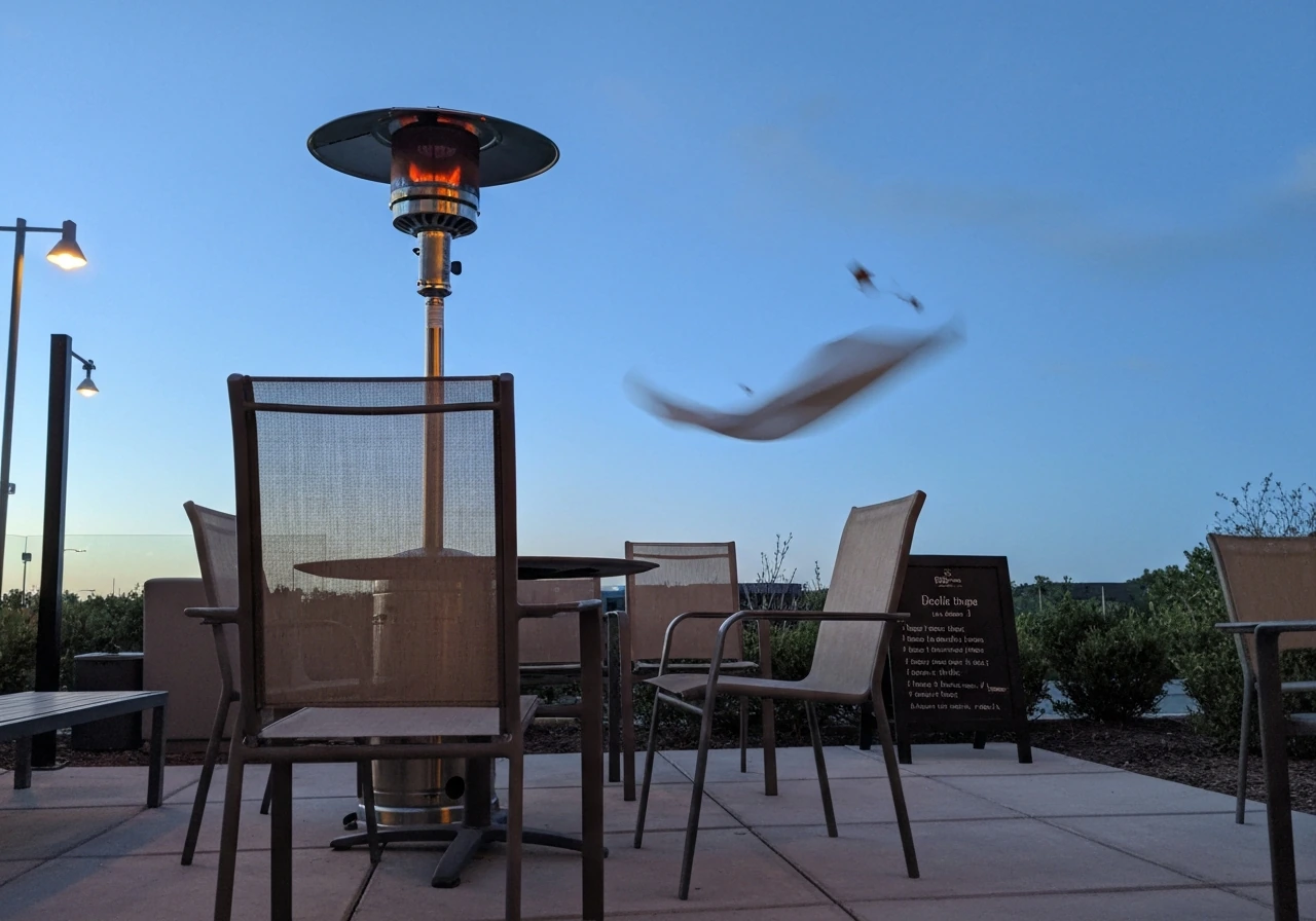 Outdoor patio heater glowing with visible wind-swept cues and comfortable seating nearby.